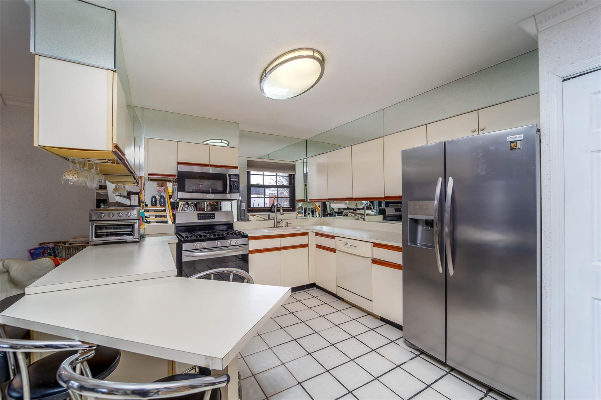 509 Julius Road Queens, NY 11356 - Photo 14 of 26 a kitchen with a refrigerator and white cabinets
