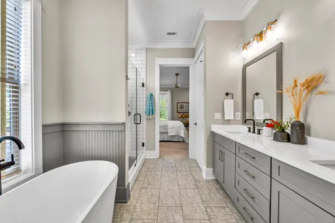 a spacious en suite bathroom with a double vanity sink a large mirror and a shower