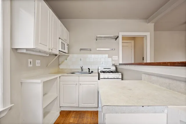 a kitchen with white cabinets and sink