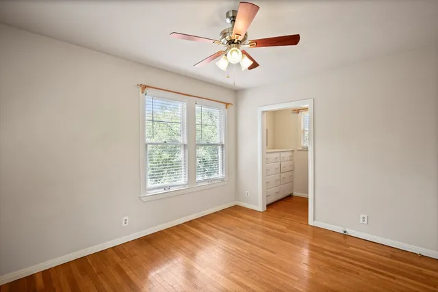 an empty room with chandelier fan and windows