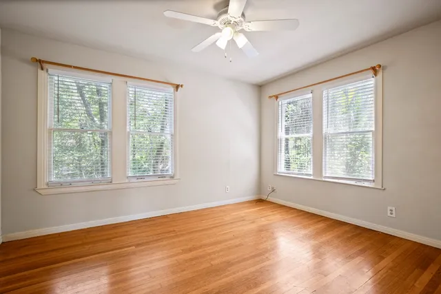 a view of an empty room with wooden floor and a window
