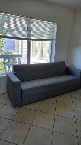 a living room with couches and large window with kitchen view