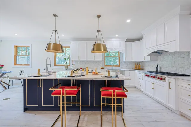 a white kitchen with stainless steel appliances granite countertop white cabinets a sink and a stove