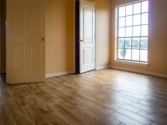 an empty room with wooden floor and windows