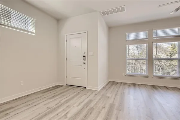 a view of an empty room with wooden floor and a window
