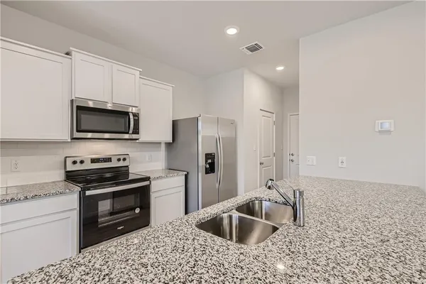 a kitchen with granite countertop a sink a counter top space and stainless steel appliances