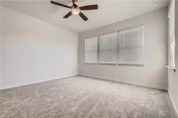 a view of a livingroom with a ceiling fan & windows