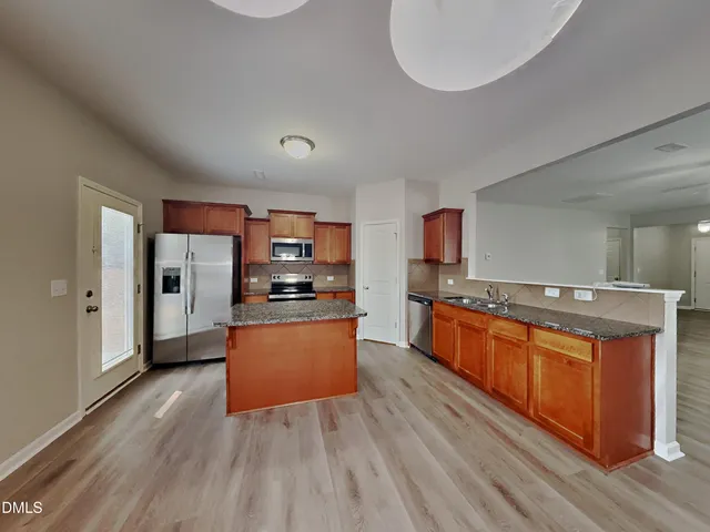 a large kitchen with stainless steel appliances wooden floors and wooden cabinets