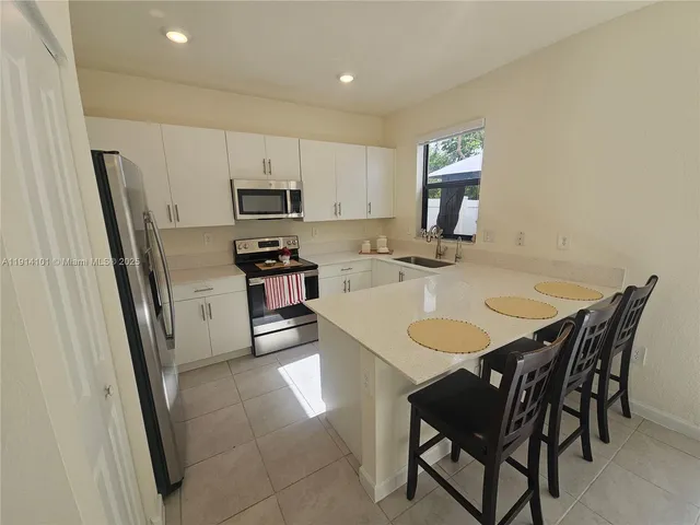 a kitchen with stainless steel appliances granite countertop a dining table chairs refrigerator and microwave