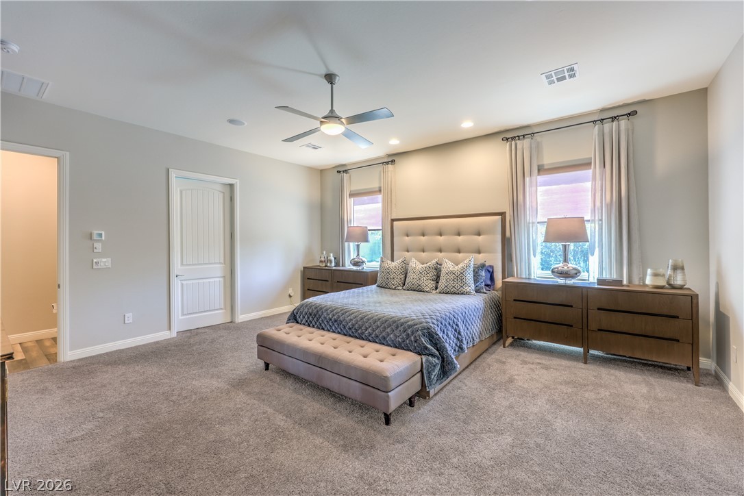 7119 Arabian Ridge Street Las Vegas, NV 89131 - Photo 27 of 73 A tranquil primary bedroom features plush carpeting, a coffered ceiling, and two large windows framing verdant outdoor views.