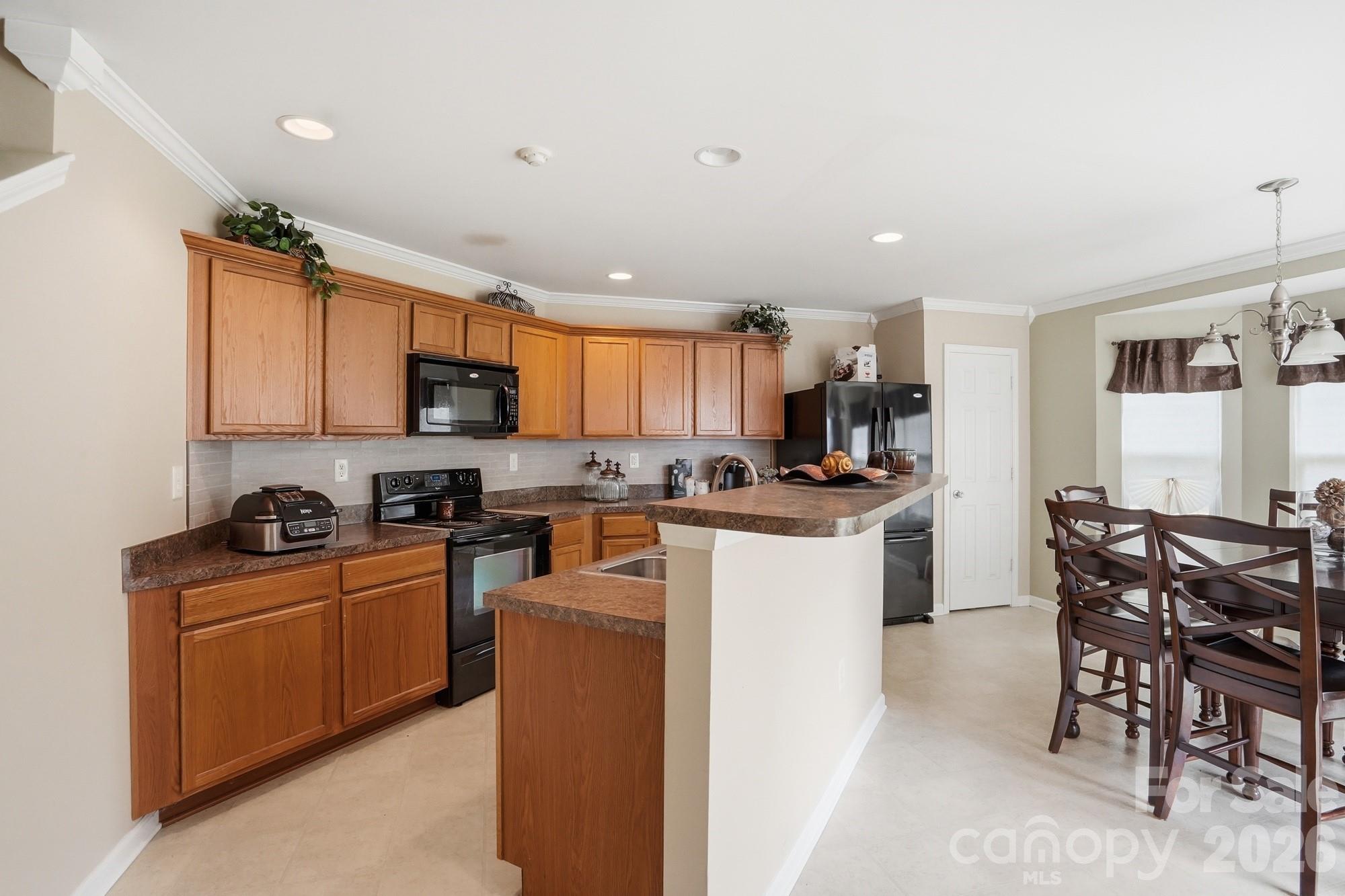 4404 Kiddle Lane Monroe, NC 28110 - Photo 13 of 48 a kitchen with stainless steel appliances granite countertop a stove top oven a sink a dining table and chairs