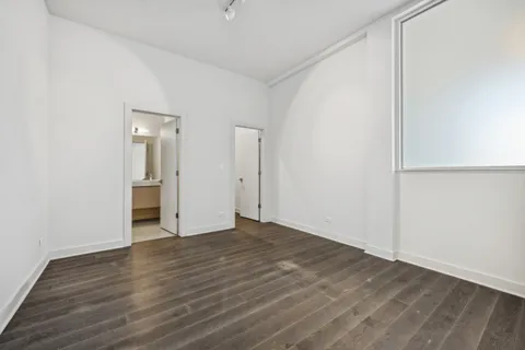 a view of an empty room with wooden floor and closet
