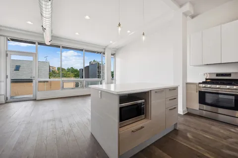a kitchen with stainless steel appliances kitchen island granite countertop a stove and a wooden floors