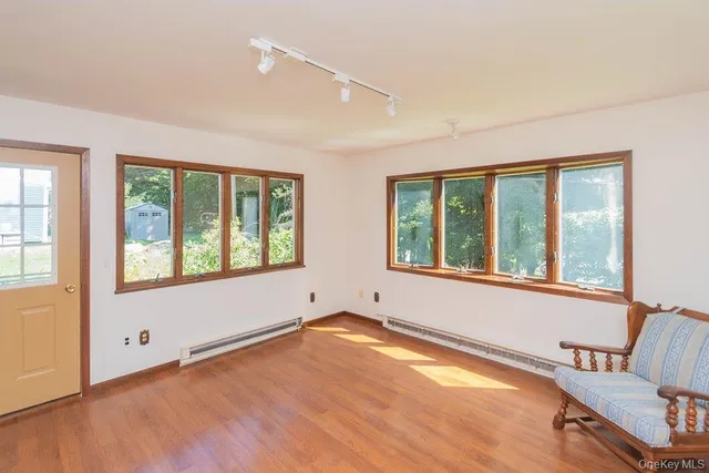 a view of an empty room with a window and wooden floor