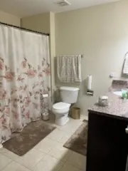 a bathroom with a granite countertop sink and a toilet