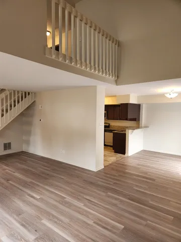 a view of kitchen and empty room with wooden floor