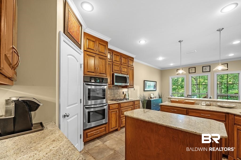 29976 Dolive Ridge Daphne, AL 36527 - Photo 24 of 58 Kitchen featuring tasteful backsplash, light tile patterned floors, light stone counters, stainless steel appliances, and decorative light fixtures