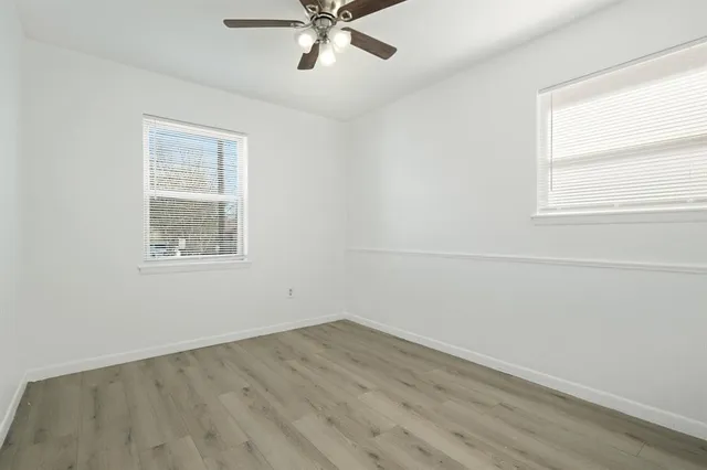 an empty room with a window and a ceiling fan