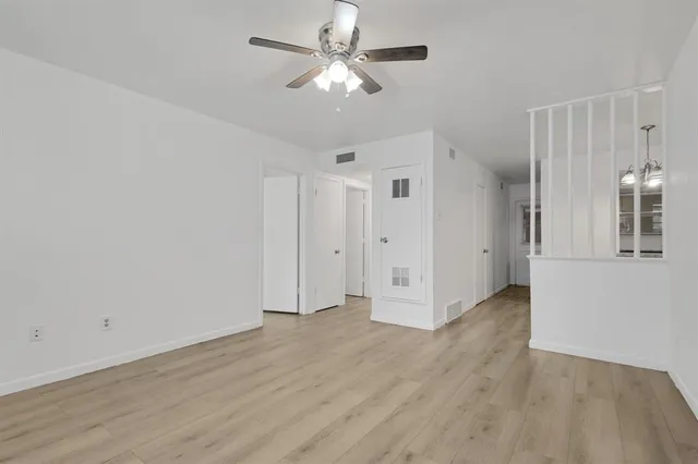 an empty room with wooden floor and a ceiling fan