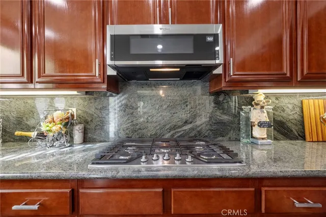 a kitchen with stainless steel appliances granite countertop a stove refrigerator and a dining table with wooden floor