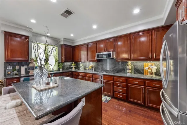 a kitchen with stainless steel appliances granite countertop wooden cabinets a refrigerator and a sink