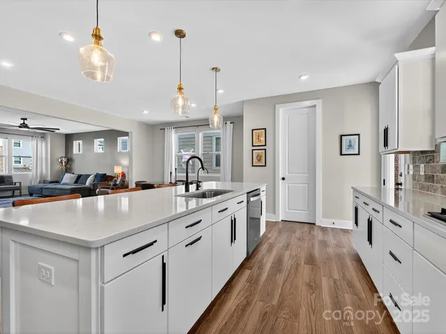 a large kitchen with kitchen island a stove a sink a refrigerator and a view of living room