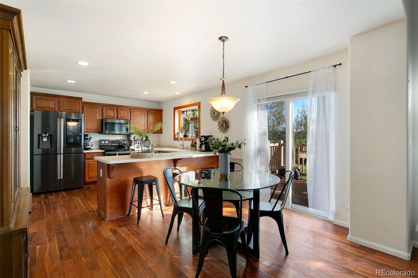 1606 Conestoga Drive Fort Lupton, CO 80621 - Photo 7 of 25 a dining area with stainless steel appliances kitchen island granite countertop a dining table chairs and a wooden floor
