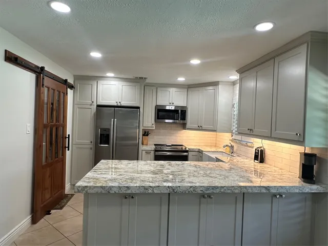 a kitchen with kitchen island granite countertop a sink refrigerator and cabinets