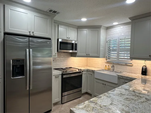 a kitchen with stainless steel appliances granite countertop a sink stove and refrigerator