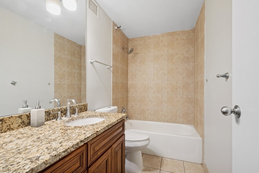 200 North Dearborn Street, Unit 2402 Chicago, IL 60601 - Photo 12 of 22 a bathroom with a granite countertop sink a toilet and shower