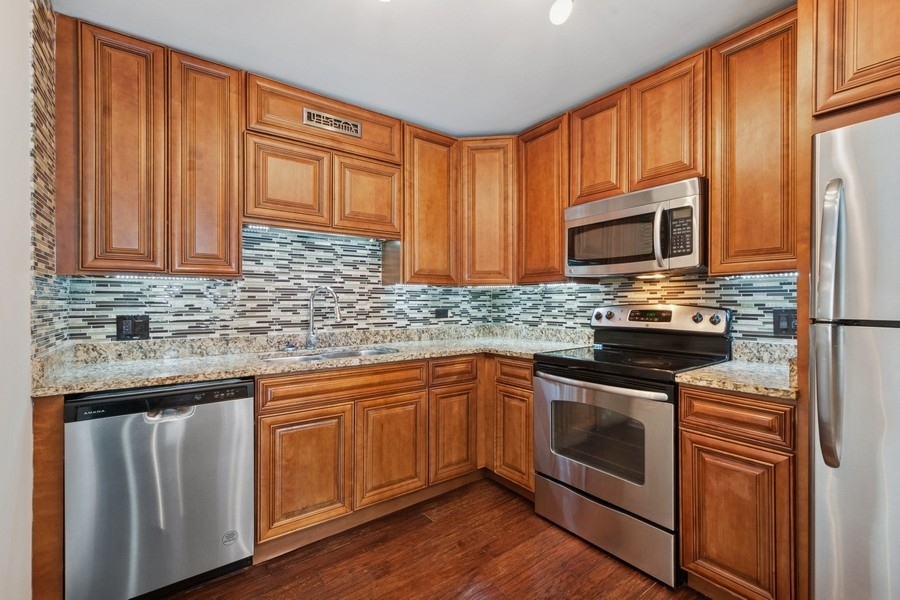 200 North Dearborn Street, Unit 2402 Chicago, IL 60601 - Photo 7 of 22 a kitchen with granite countertop wooden cabinets stainless steel appliances and a sink