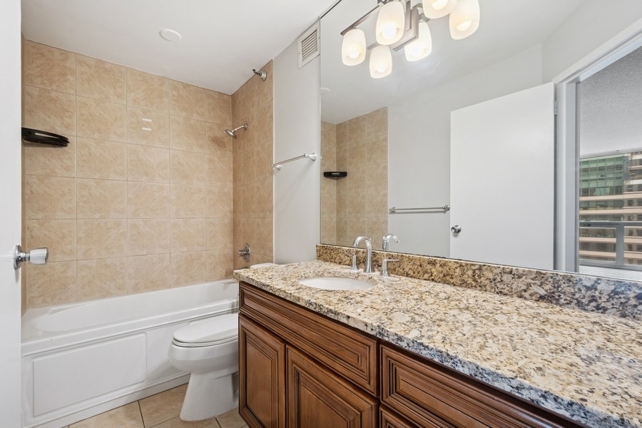200 North Dearborn Street, Unit 2402 Chicago, IL 60601 - Photo 10 of 22 a bathroom with a granite countertop sink a toilet and bathtub