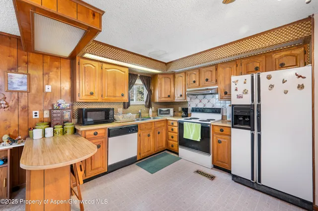 a kitchen with stainless steel appliances granite countertop a refrigerator a stove top oven a sink dishwasher and white cabinets