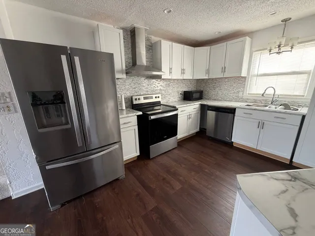 a kitchen with granite countertop stainless steel appliances a sink a refrigerator a window and cabinets