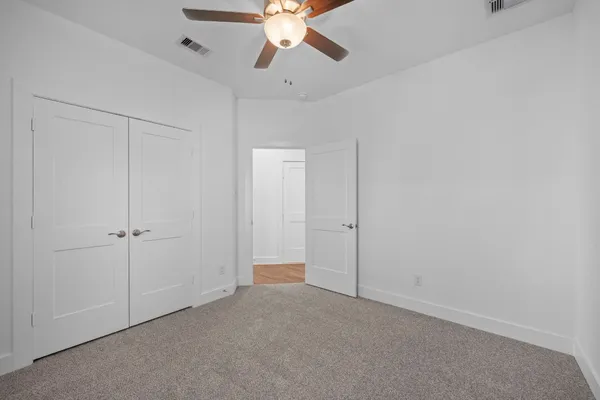 a view of an empty room and chandelier fan