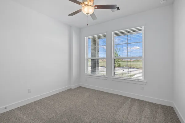 an empty room with a window and a fan