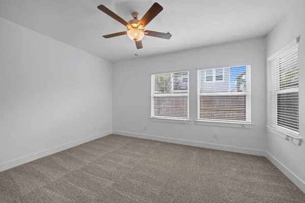 an empty room with a window and a ceiling fan
