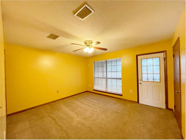 an empty room with a ceiling fan and a window