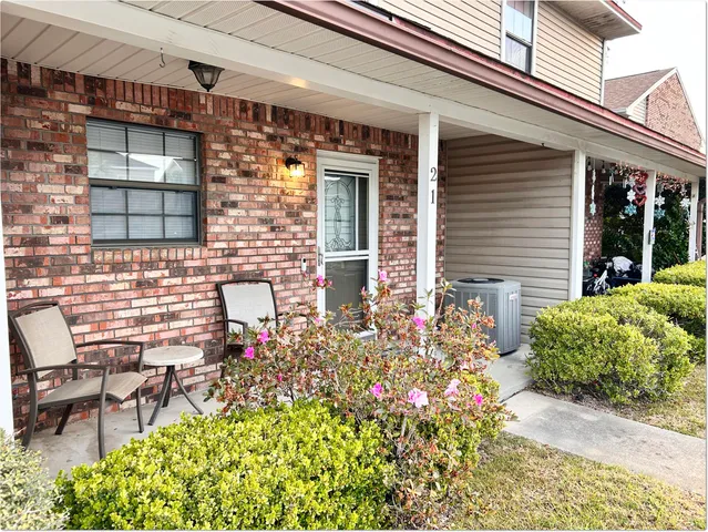 front view of a brick house with a chairs and table in a patio