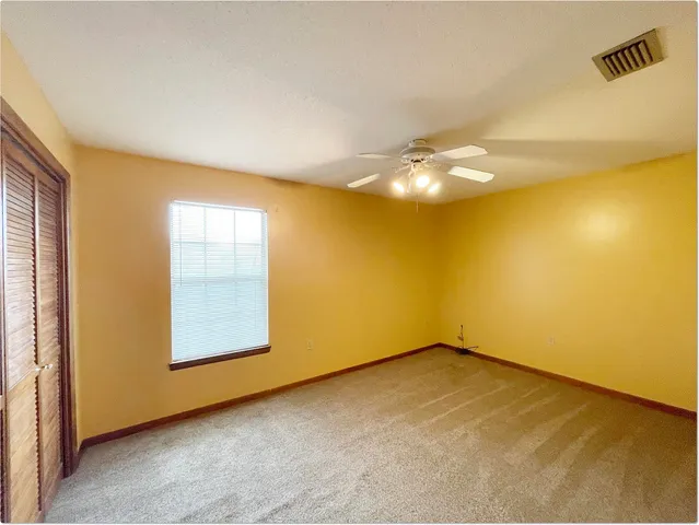 an empty room with a chandelier fan and windows