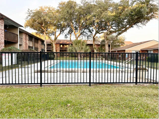 a view of a brick house in front of a yard with wooden fence