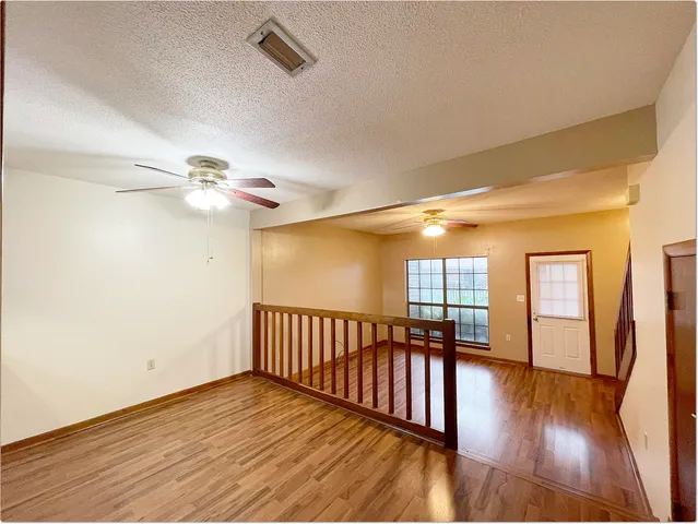 a view of empty room with wooden floor and fan
