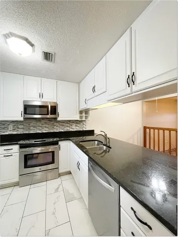 a kitchen with granite countertop a stove sink and cabinets