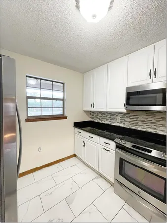 a kitchen with granite countertop white cabinets and white appliances