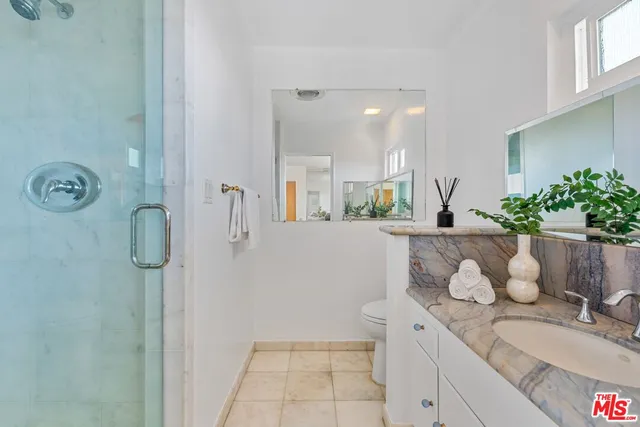 a bathroom with a granite countertop sink a mirror and shower