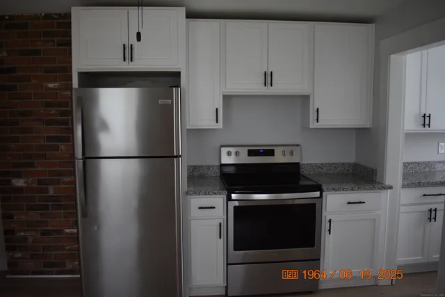 a kitchen with stainless steel appliances granite countertop a stove a refrigerator and a cabinets