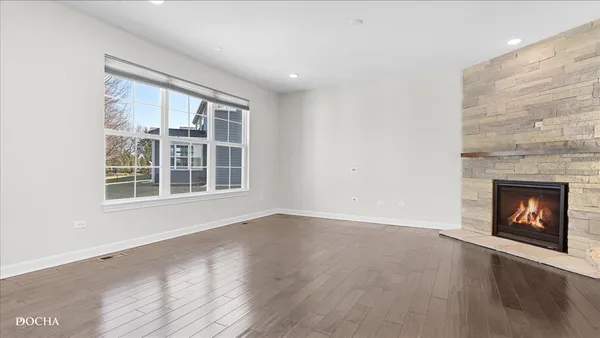 an empty room with wooden floor fireplace and windows