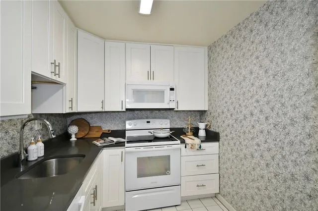 a kitchen with granite countertop white cabinets and white appliances