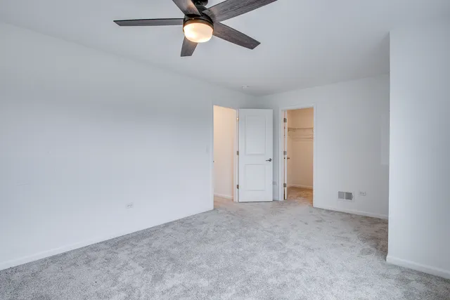 an empty room with a ceiling fan and window
