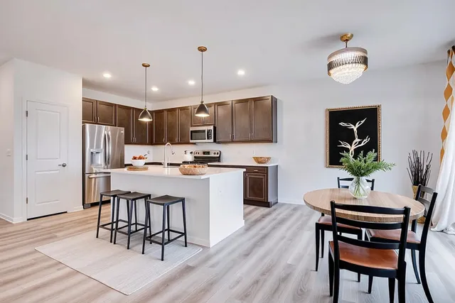 a kitchen with a dining table chairs refrigerator and microwave